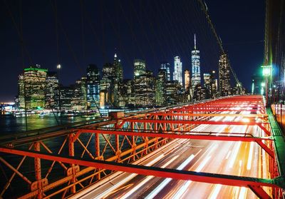 Light trails on city street amidst buildings against sky at night. brooklyn bridge new york at night 