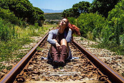 Woman sitting on railroad track