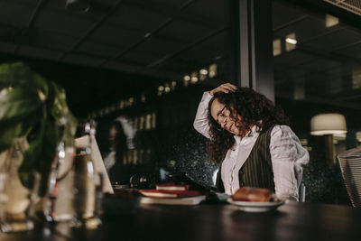 Woman sitting at restaurant table in cafe