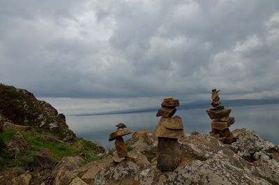 Stack of rocks by sea against sky