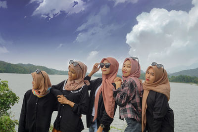 Group of friends standing on beach against sky