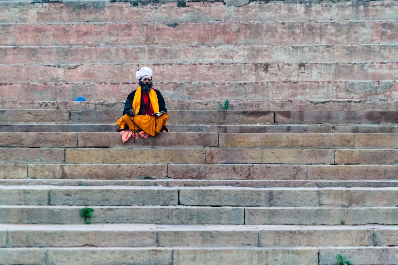 LOW ANGLE VIEW OF MAN CLIMBING UP AGAINST WALL