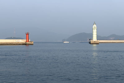 Lighthouse by sea against clear sky