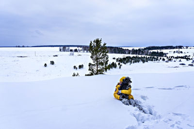 People on snow covered land against sky