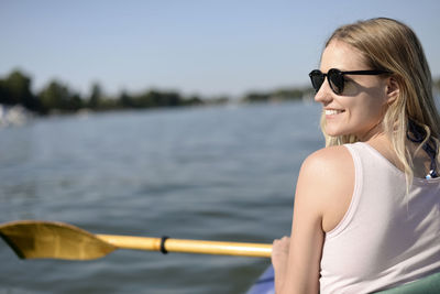 Rear view of young woman smiling while sailing boat in lake