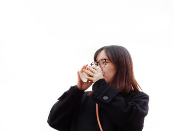 Portrait of young woman standing against white background