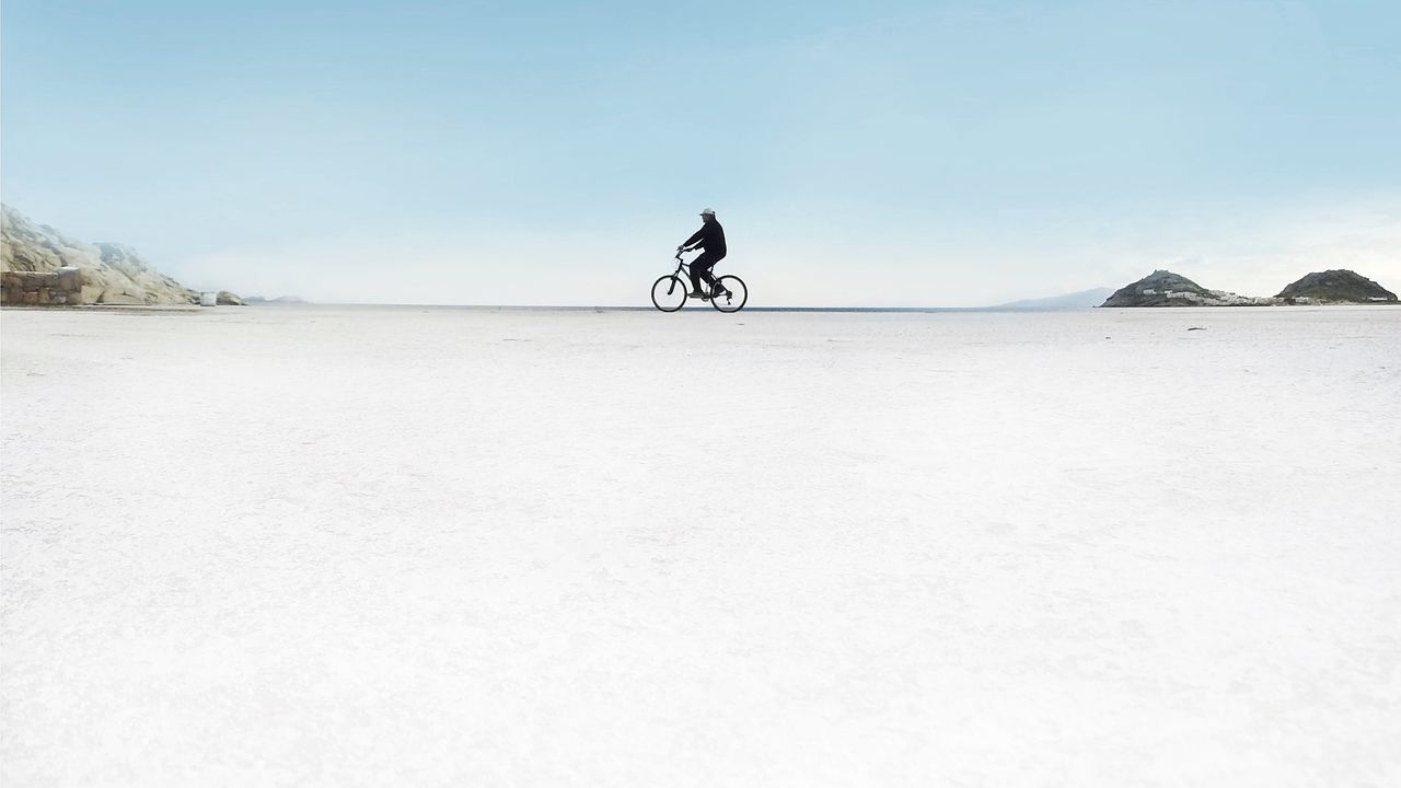 clear sky, copy space, leisure activity, men, transportation, lifestyles, tranquility, tranquil scene, mountain, bicycle, scenics, nature, beach, sand, full length, day, sunlight, mode of transport