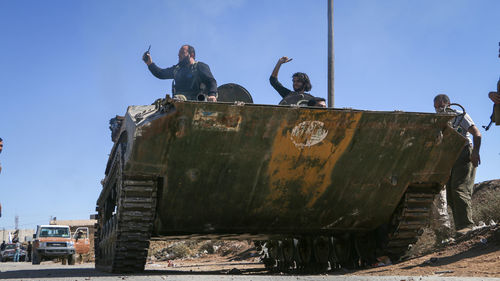 People on rusty boat against clear sky