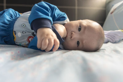 Portrait of cute baby lying on bed at home