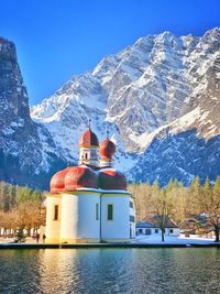 Built structure by snowcapped mountain against sky