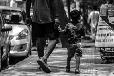 Rear view of people walking on sidewalk in city