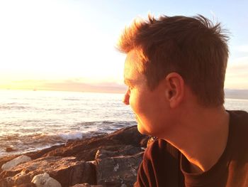 Boy looking at sea shore against clear sky