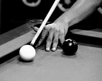 Hand aiming at cue ball on pool table