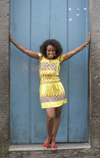 Portrait of young woman standing against door