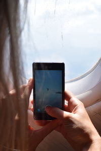 Cropped image of woman photographing in airplane