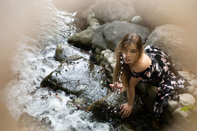 High angle view portrait of smiling woman standing by rock