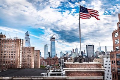 American flag on modern buildings in city against sky