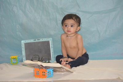 Portrait of shirtless boy sitting on table