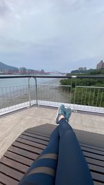 Low section of man lying on railing against sky