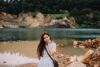 Young woman standing against lake