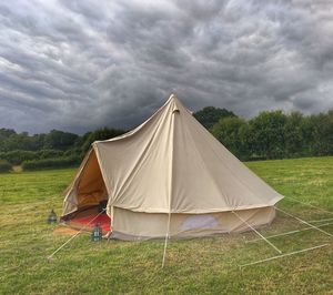 Tent on landscape against cloudy sky