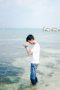 Full length of man standing in sea against sky