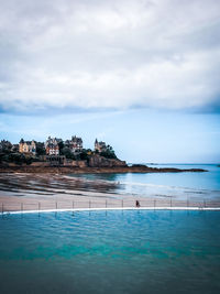 View of swimming pool at beach against cloudy sky