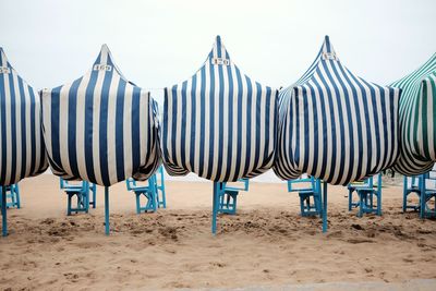 Row of umbrellas on beach against sky