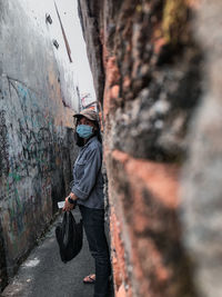 Side view of man standing against graffiti wall