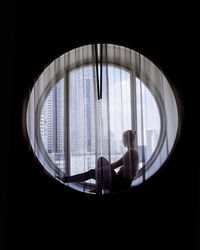 Silhouette of woman doing yoga in the round window