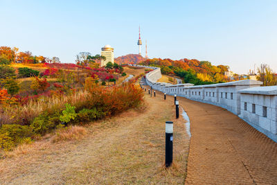 Footpath amidst buildings against sky during autumn