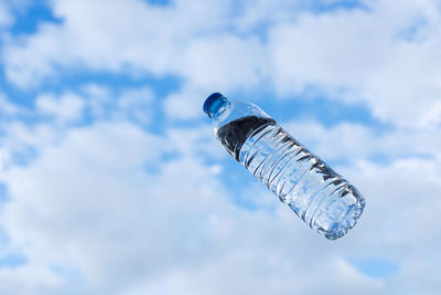 Close-up of glass bottle against blue sky