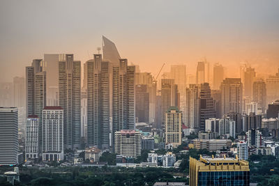 Modern buildings in city against sky during sunset