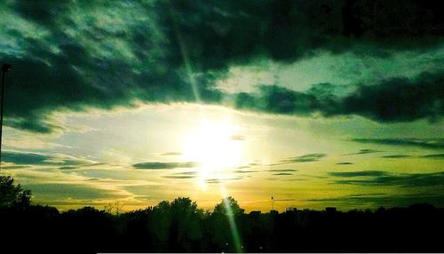 Low angle view of sun shining through clouds