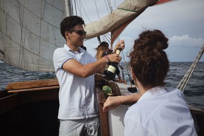 Young man holding sailboat in sea against sky