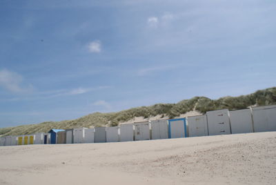 Beach huts on sand against sky