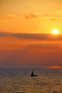 Silhouette sailboat in sea against sky during sunset