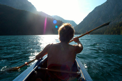 Rear view of man on boat in sea against sky