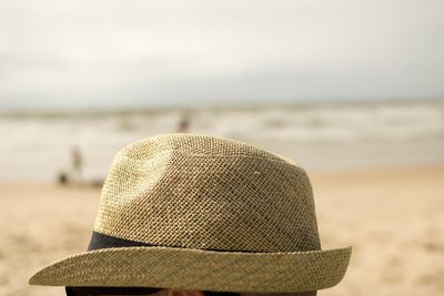 Close-up of hat on beach against sky