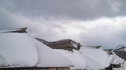 Low angle view of snow covered built structures against sky