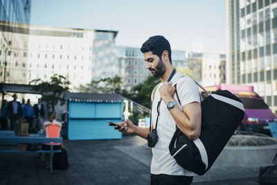 Side view of male tourist using smart phone in city