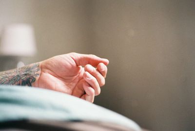 Close-up of person hand on bed at home