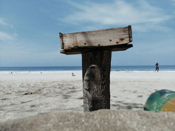 Wooden post at beach against sky