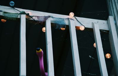 Low angle view of string lights on railing at night