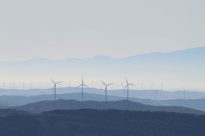 Wind turbines on landscape against sky