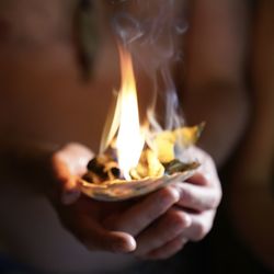 Close-up of hand holding burning candle