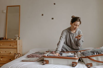 Woman checking backpack before going to airport, open suitcase on the bed