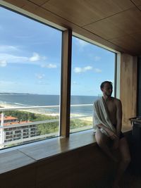 Young woman looking through window