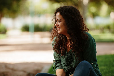 Smiling woman looking away while sitting outdoors