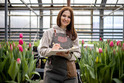 Portrait of young woman standing by plants
